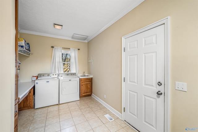 laundry area with cabinet space, light tile patterned floors, crown molding, washing machine and dryer, and a sink