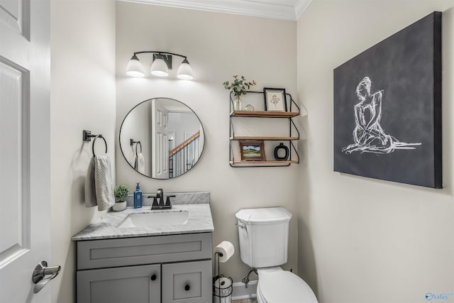 half bathroom with ornamental molding, vanity, and toilet