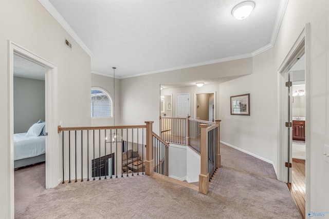 hallway with carpet, ornamental molding, baseboards, and an upstairs landing