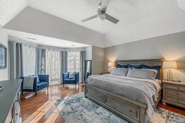 bedroom featuring vaulted ceiling, a textured ceiling, wood finished floors, and a ceiling fan