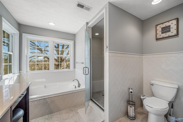 bathroom with visible vents, a garden tub, a textured ceiling, and a shower stall