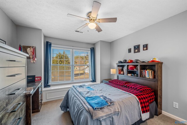 bedroom with baseboards, visible vents, ceiling fan, carpet, and a textured ceiling