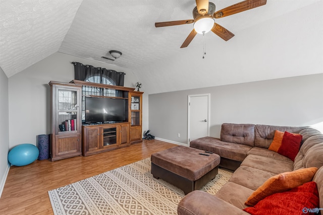 living room with a ceiling fan, vaulted ceiling, a textured ceiling, and wood finished floors