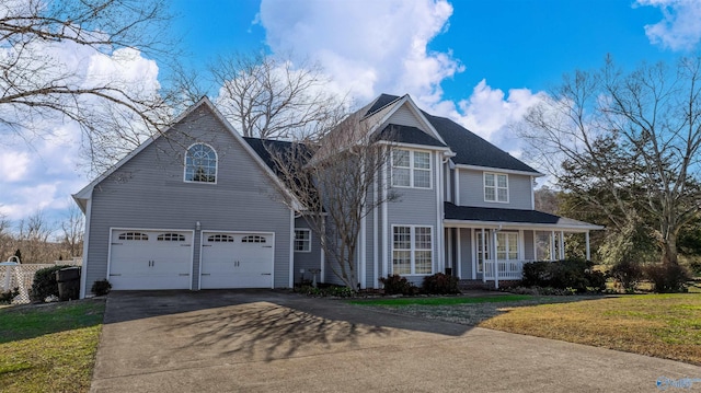 traditional home featuring a porch, a front lawn, a garage, and aphalt driveway