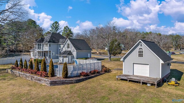 rear view of property featuring a yard, an outdoor structure, stairway, and fence