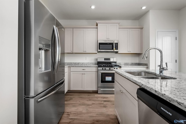 kitchen featuring light stone counters, appliances with stainless steel finishes, sink, and white cabinets