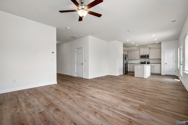 unfurnished living room featuring ceiling fan and light wood-type flooring