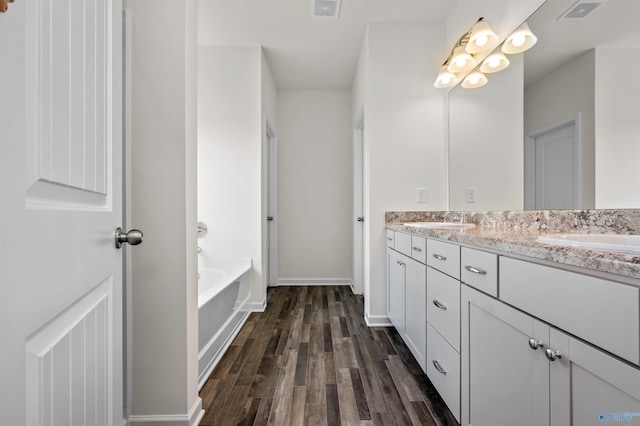 bathroom with vanity, hardwood / wood-style flooring, and a tub