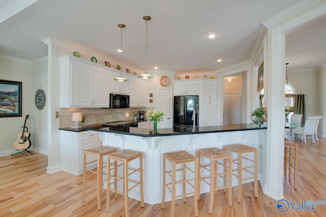 227 Lee Bowden Dr, Huntsville, AL 35806 - kitchen featuring black appliances, decorative backsplash, light wood-type flooring, a kitchen bar, and recessed lighting
