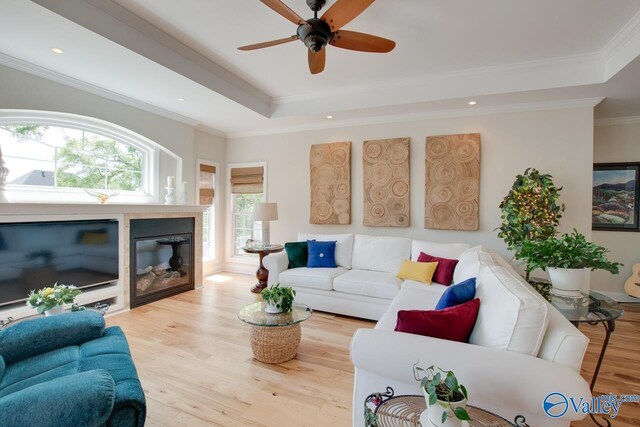 227 Lee Bowden Dr, Huntsville, AL 35806 - living room with wood finished floors, a raised ceiling, ceiling fan, a glass covered fireplace, and crown molding