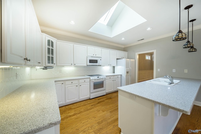 kitchen featuring a sink, backsplash, white appliances, a peninsula, and a skylight