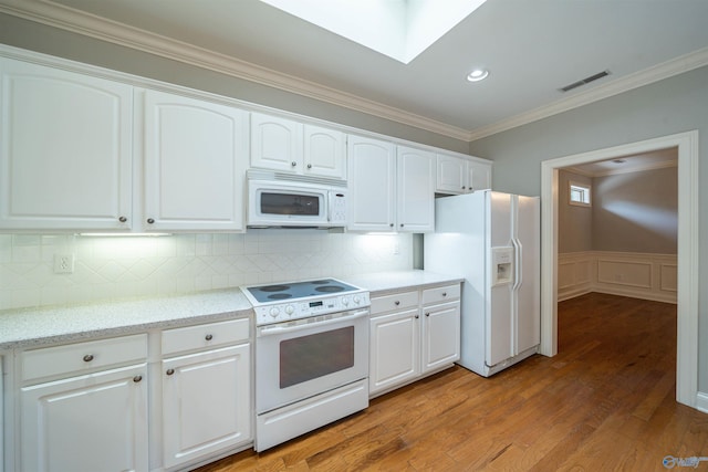 kitchen featuring visible vents, white cabinetry, white appliances, a skylight, and crown molding