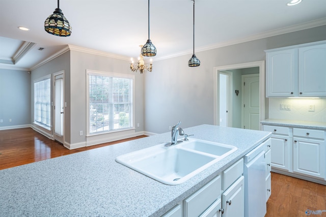 kitchen featuring a sink, light wood-style flooring, pendant lighting, and ornamental molding