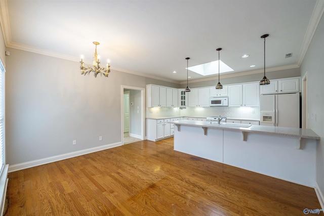 kitchen featuring a kitchen breakfast bar, white cabinetry, white appliances, light wood-style floors, and decorative backsplash
