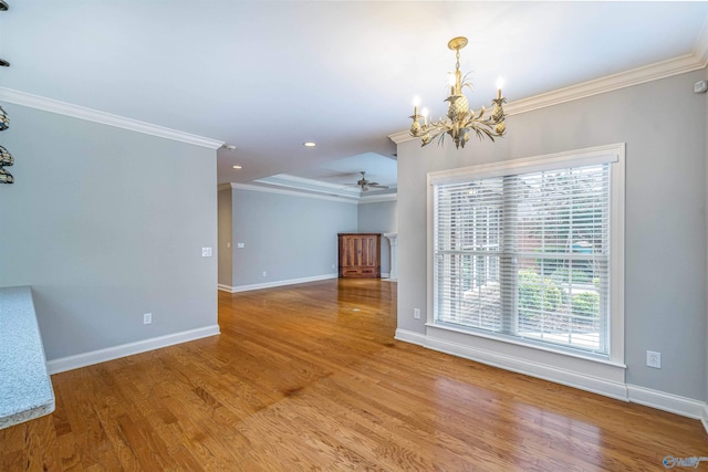 empty room with ceiling fan with notable chandelier, crown molding, a healthy amount of sunlight, and wood finished floors