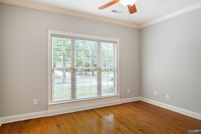 spare room with a ceiling fan, crown molding, wood finished floors, and baseboards