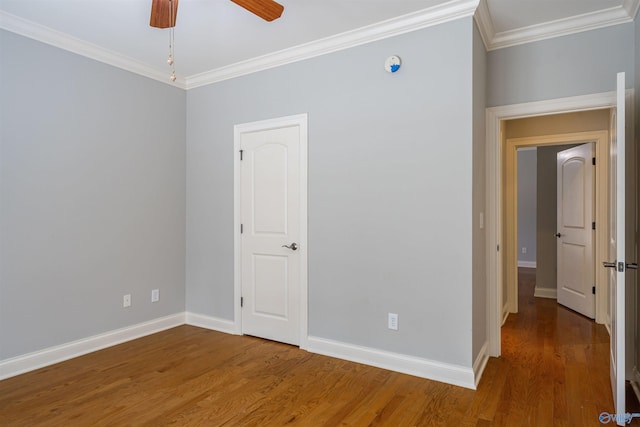 spare room with ornamental molding, a ceiling fan, baseboards, and wood finished floors