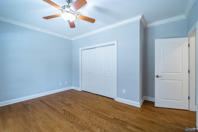 unfurnished bedroom featuring wood finished floors, a closet, crown molding, baseboards, and ceiling fan