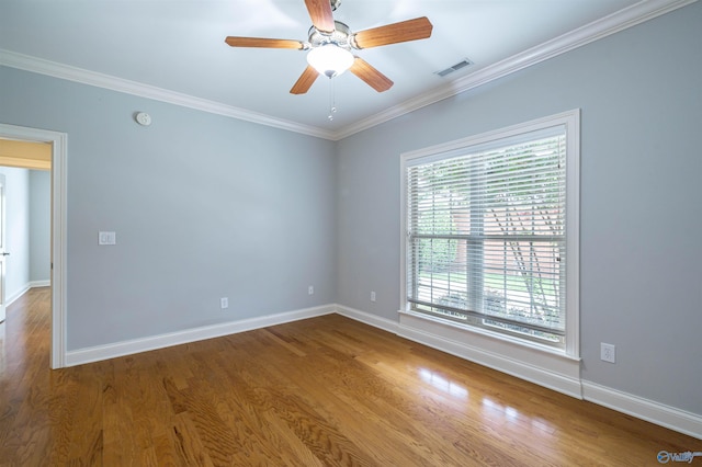 unfurnished room with visible vents, crown molding, baseboards, wood finished floors, and a ceiling fan