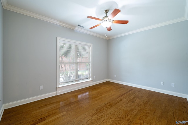 empty room with crown molding, wood finished floors, and baseboards