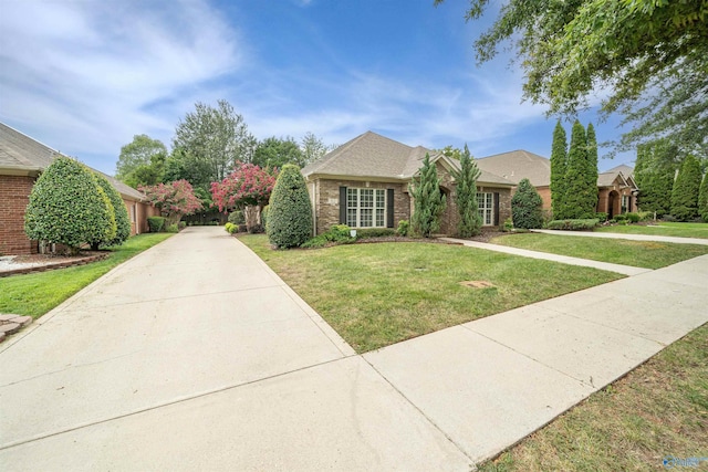view of front of property with a front yard, brick siding, and driveway