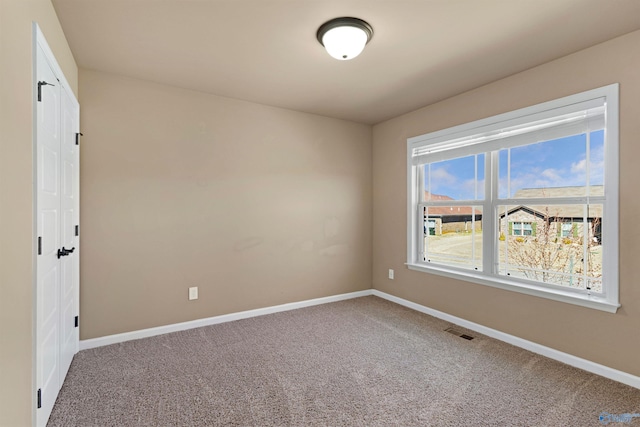 carpeted spare room featuring visible vents and baseboards