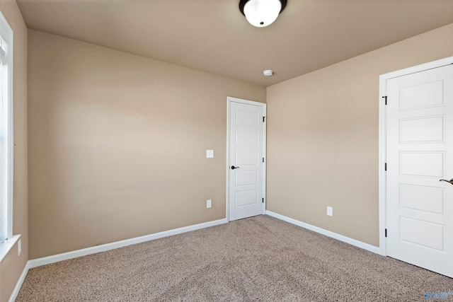 unfurnished room with carpet and baseboards