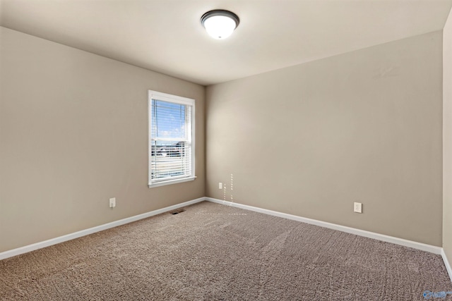 empty room with carpet floors, visible vents, and baseboards