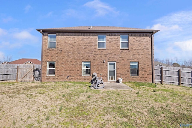 back of house featuring a yard, a fenced backyard, a patio, and brick siding