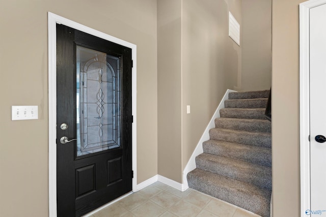 foyer featuring stairs, light tile patterned flooring, and baseboards