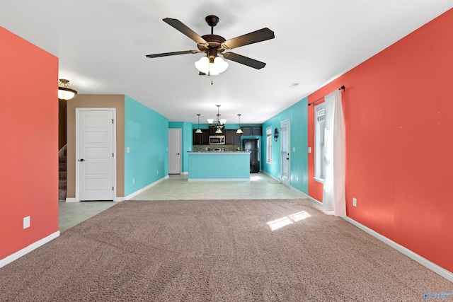 unfurnished living room with a ceiling fan, light colored carpet, stairway, and baseboards