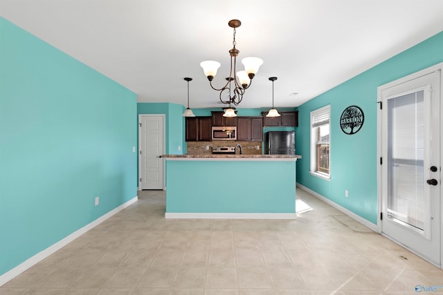 kitchen featuring dark brown cabinetry, decorative backsplash, stainless steel appliances, a chandelier, and pendant lighting