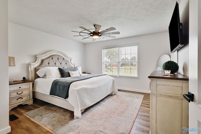 bedroom featuring ceiling fan, a textured ceiling, and light hardwood / wood-style floors