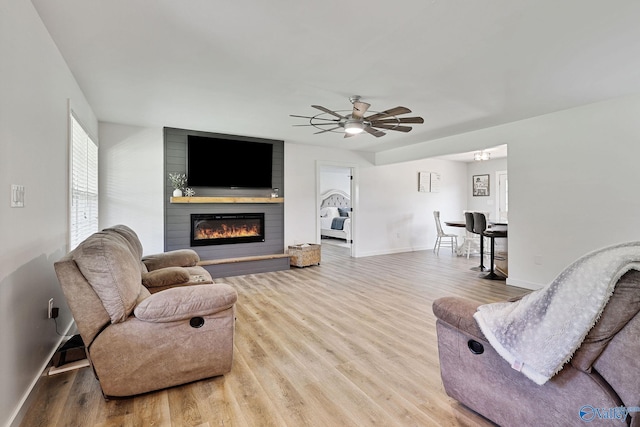 living room featuring a ceiling fan, wood finished floors, a fireplace, and baseboards