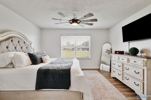 bedroom with ceiling fan, a textured ceiling, and dark wood-type flooring