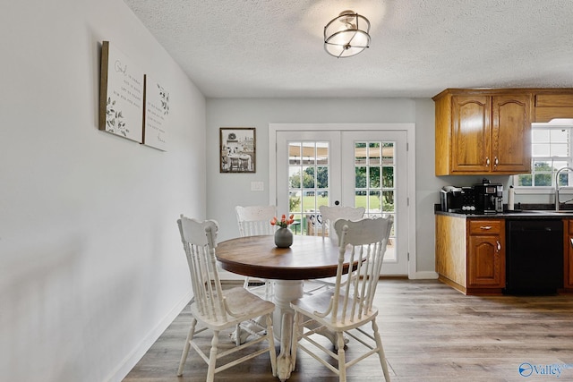 dining space featuring light wood-style flooring, french doors, a textured ceiling, and baseboards