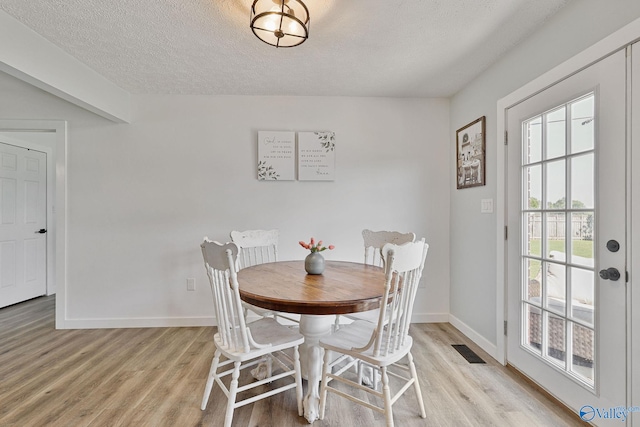 dining room featuring a textured ceiling and light hardwood / wood-style flooring