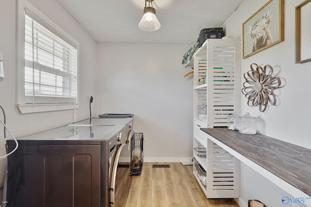 laundry room featuring light wood finished floors, visible vents, laundry area, independent washer and dryer, and a textured ceiling