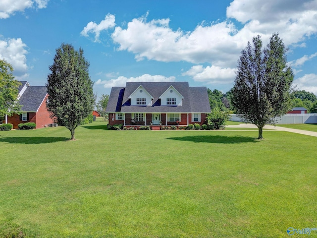 cape cod-style house featuring covered porch, a front yard, and fence