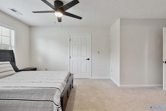 bedroom with a ceiling fan, visible vents, baseboards, a textured ceiling, and light colored carpet