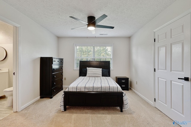 carpeted bedroom with ceiling fan, a textured ceiling, and ensuite bathroom