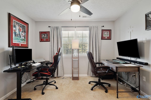 carpeted office with a textured ceiling, baseboards, visible vents, and ceiling fan