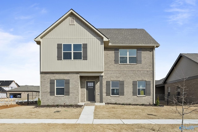 view of front of home with brick siding, board and batten siding, roof with shingles, and fence