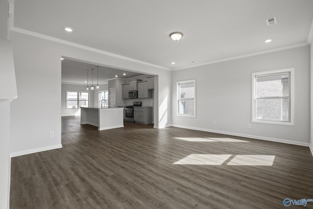 unfurnished living room featuring a sink, baseboards, ornamental molding, and dark wood-style flooring