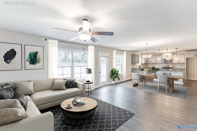 living room featuring dark wood-type flooring, sink, and ceiling fan with notable chandelier