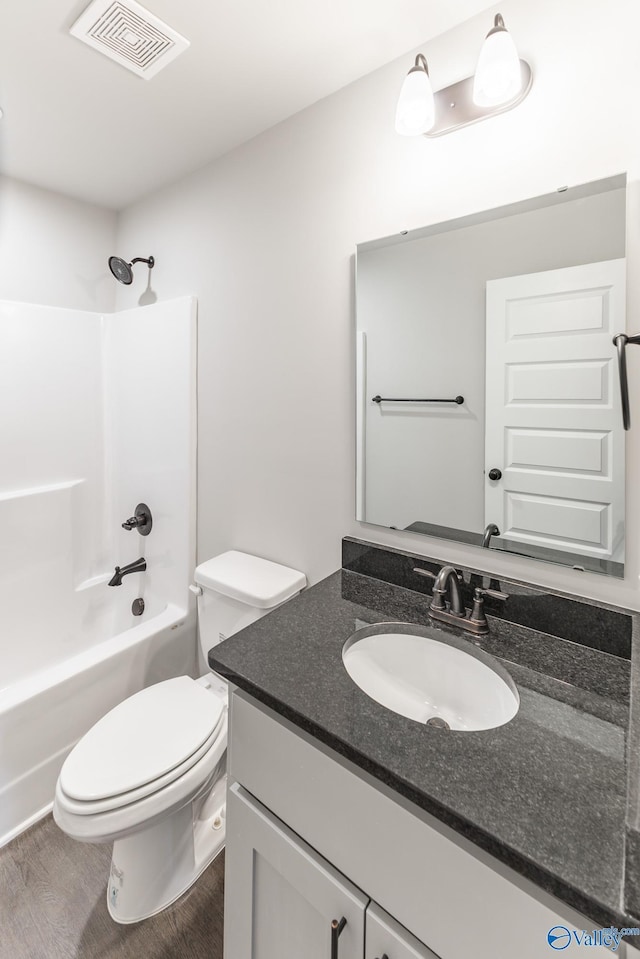 full bathroom featuring wood-type flooring, toilet, bathing tub / shower combination, and vanity