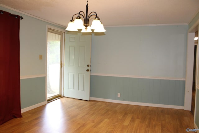 empty room with wood finished floors, crown molding, baseboards, and an inviting chandelier