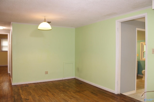 empty room featuring hardwood / wood-style flooring, baseboards, crown molding, and a textured ceiling