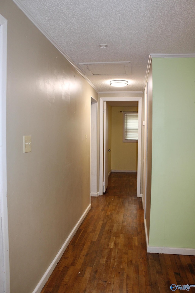 corridor featuring attic access, a textured ceiling, ornamental molding, and wood-type flooring