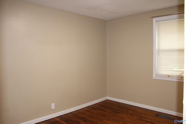 unfurnished room with baseboards, dark wood-type flooring, visible vents, and a textured ceiling